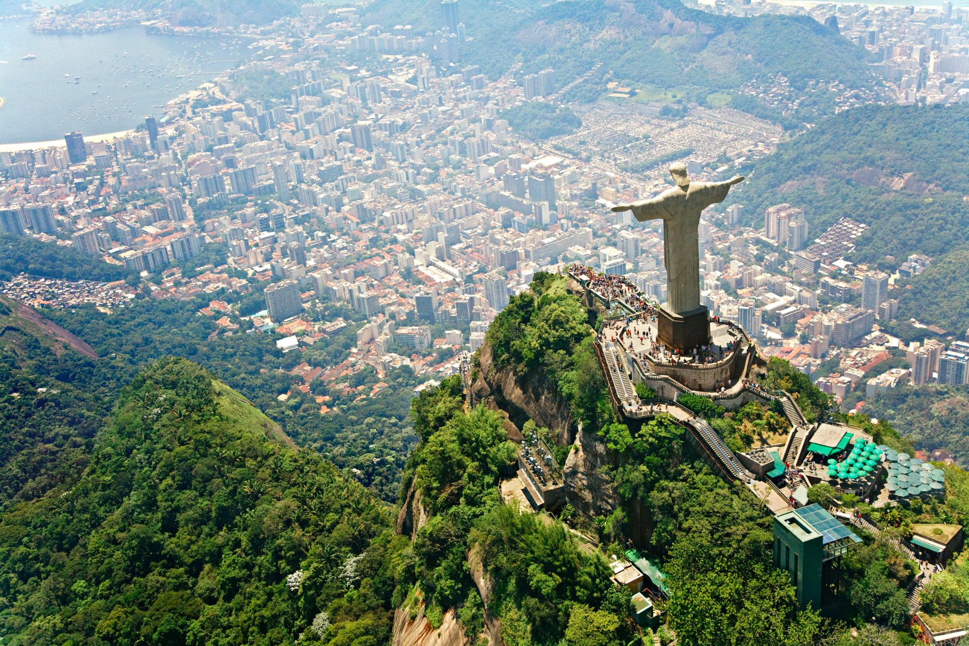 A statue of jesus is sitting on top of a hill overlooking a city.