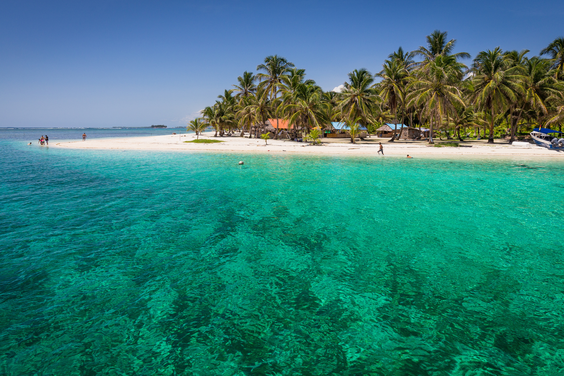 There is a small island in the middle of the ocean surrounded by palm trees.