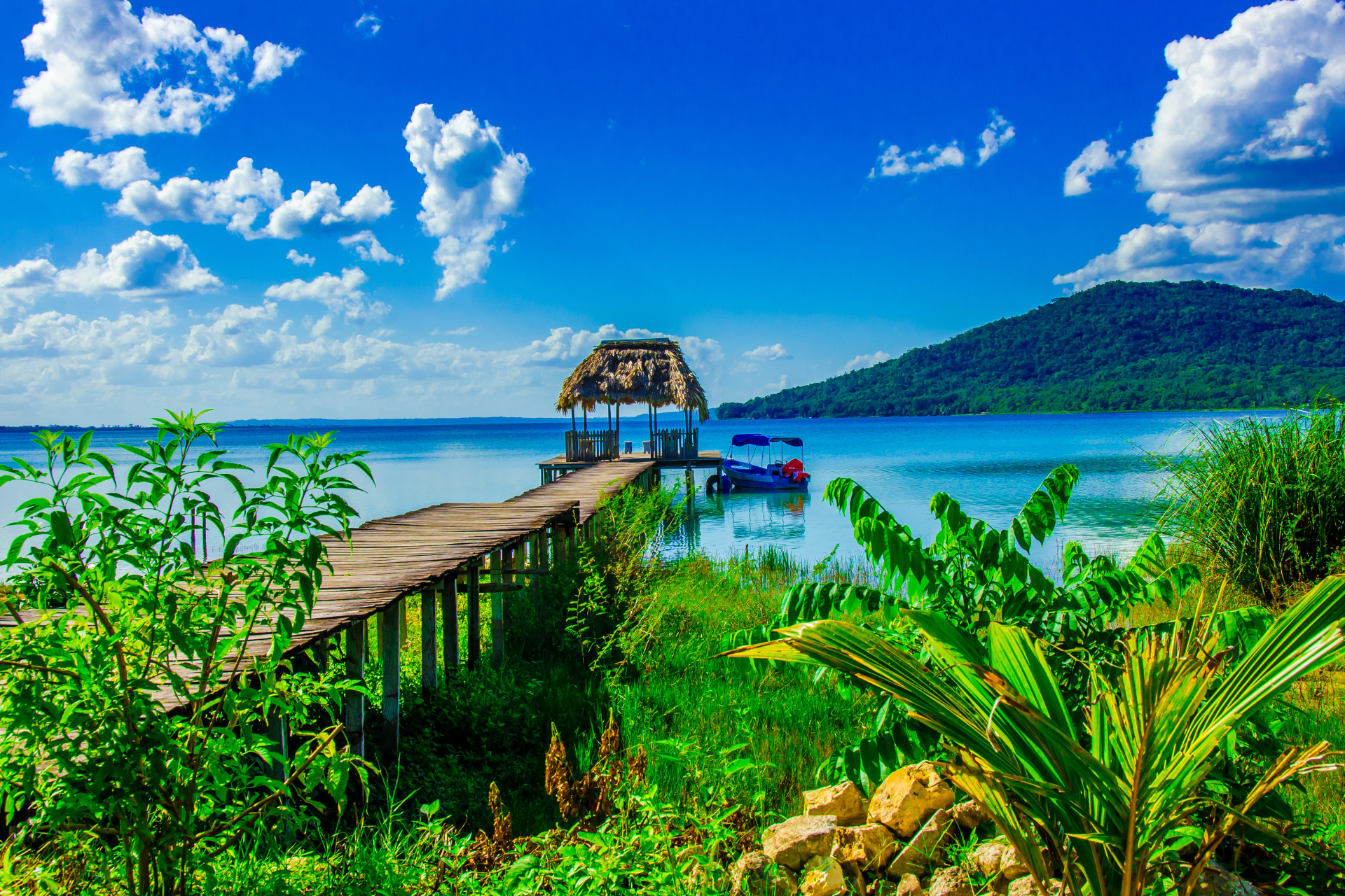 A wooden pier leading to a body of water with a hut on top of it.