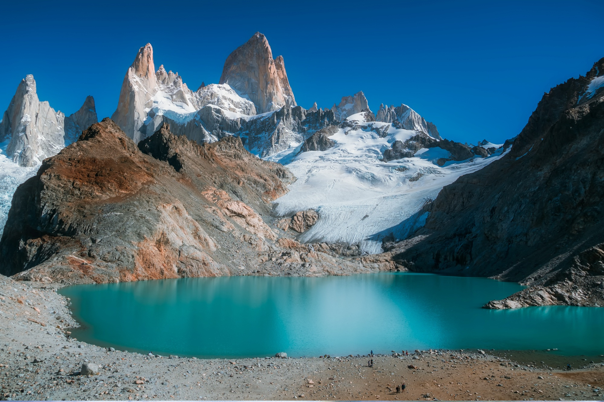 There is a lake in the middle of a mountain surrounded by snow covered mountains.