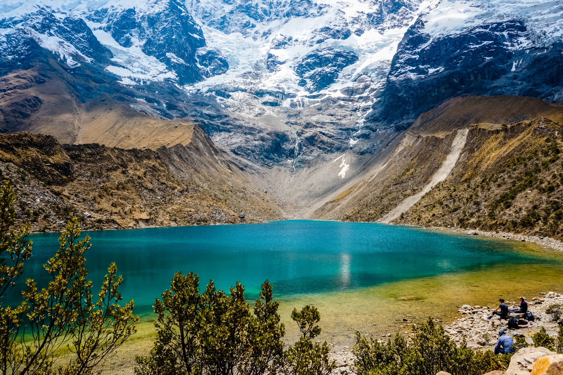 A lake in the middle of a mountain surrounded by snow covered mountains.