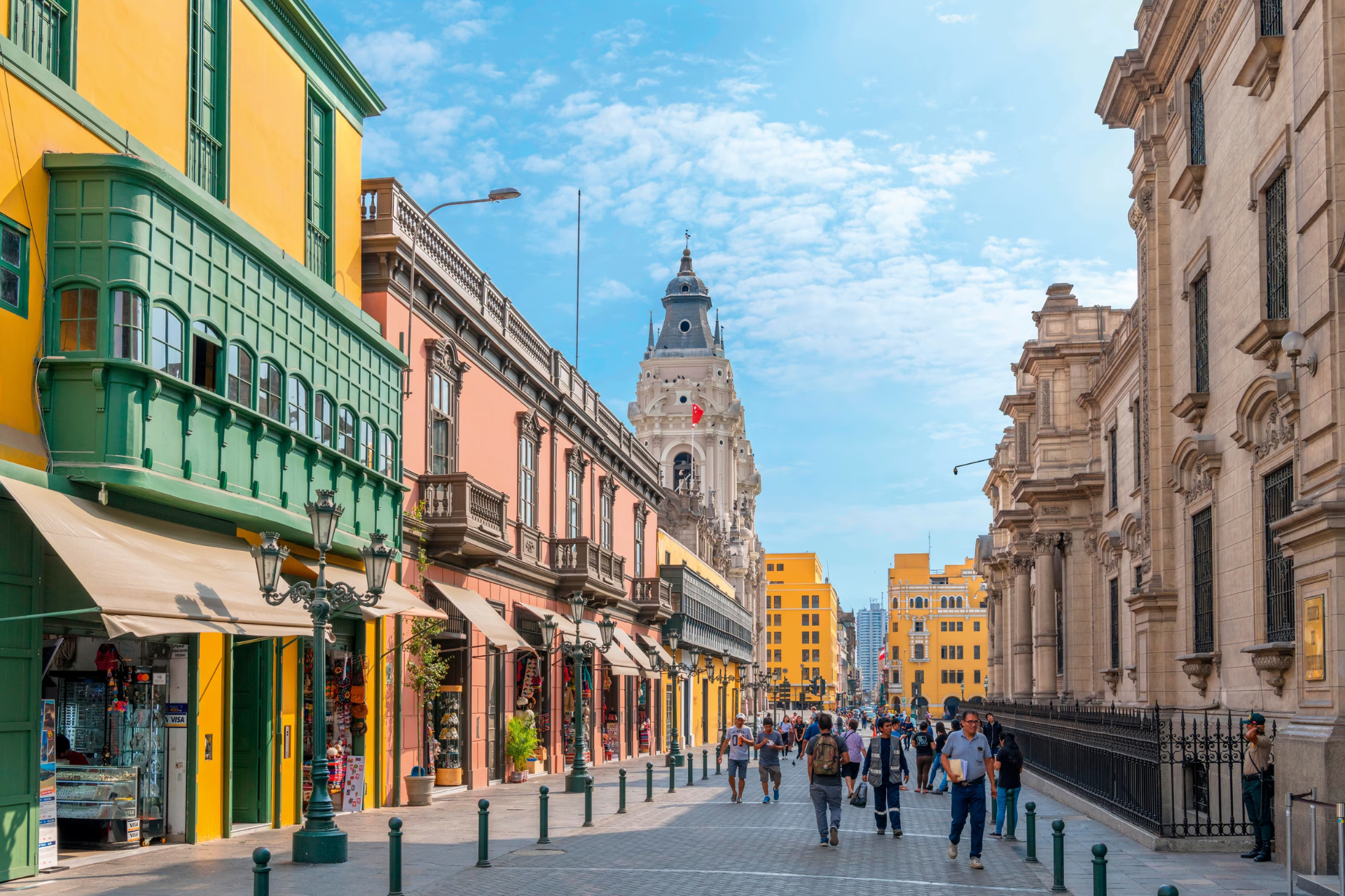 A group of people are walking down a narrow street in a city.