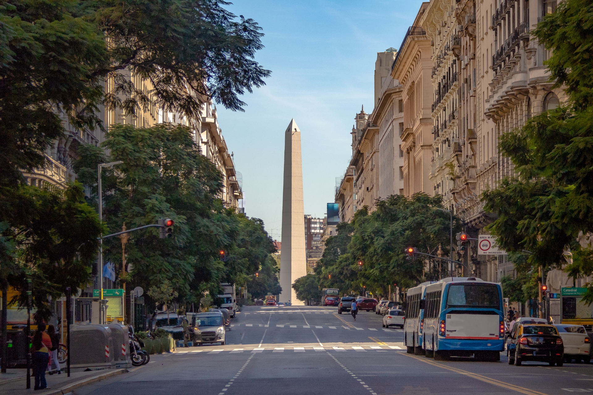 A city street with a large obelisk in the background.