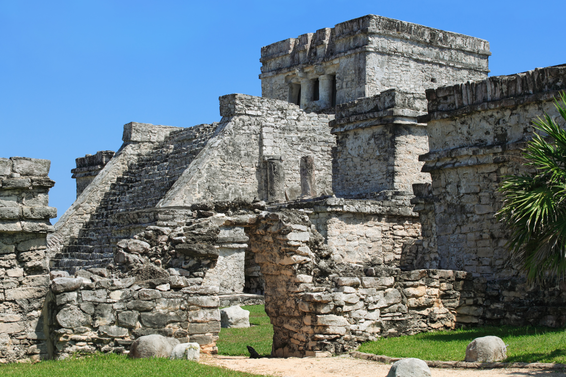 A large stone building with stairs and a tower in the middle of a field.