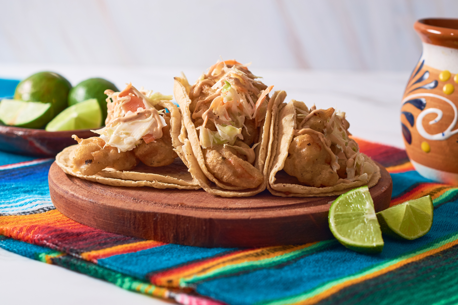 A wooden cutting board topped with tacos and limes on a table.