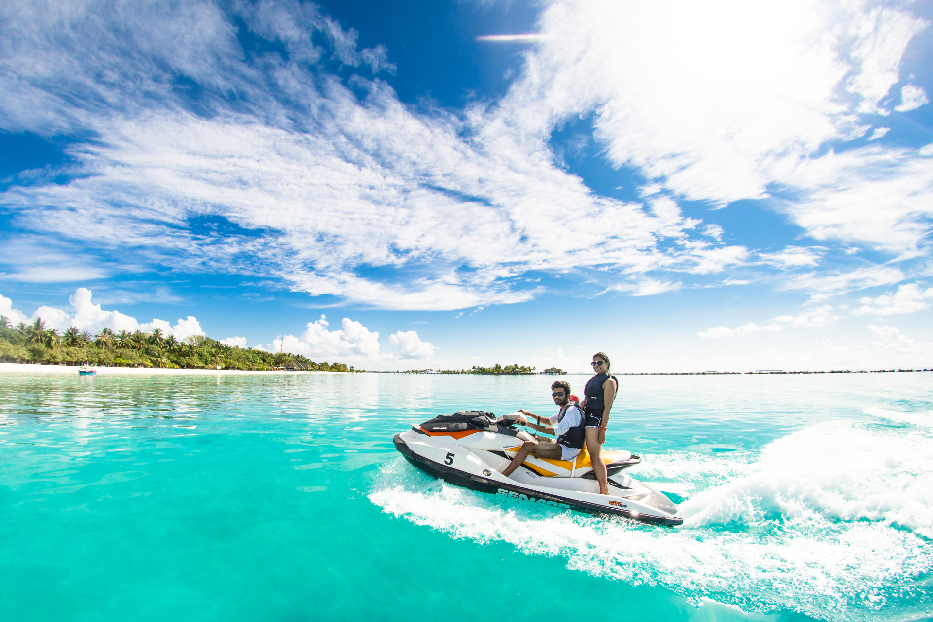 A couple is riding a jet ski in the ocean.