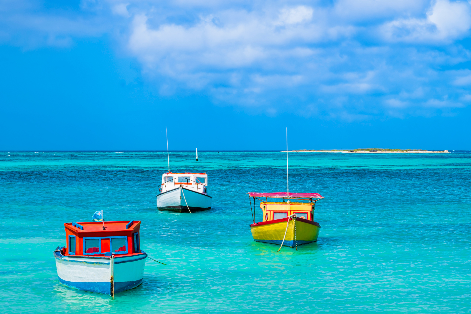 Three boats are floating on top of a turquoise ocean.