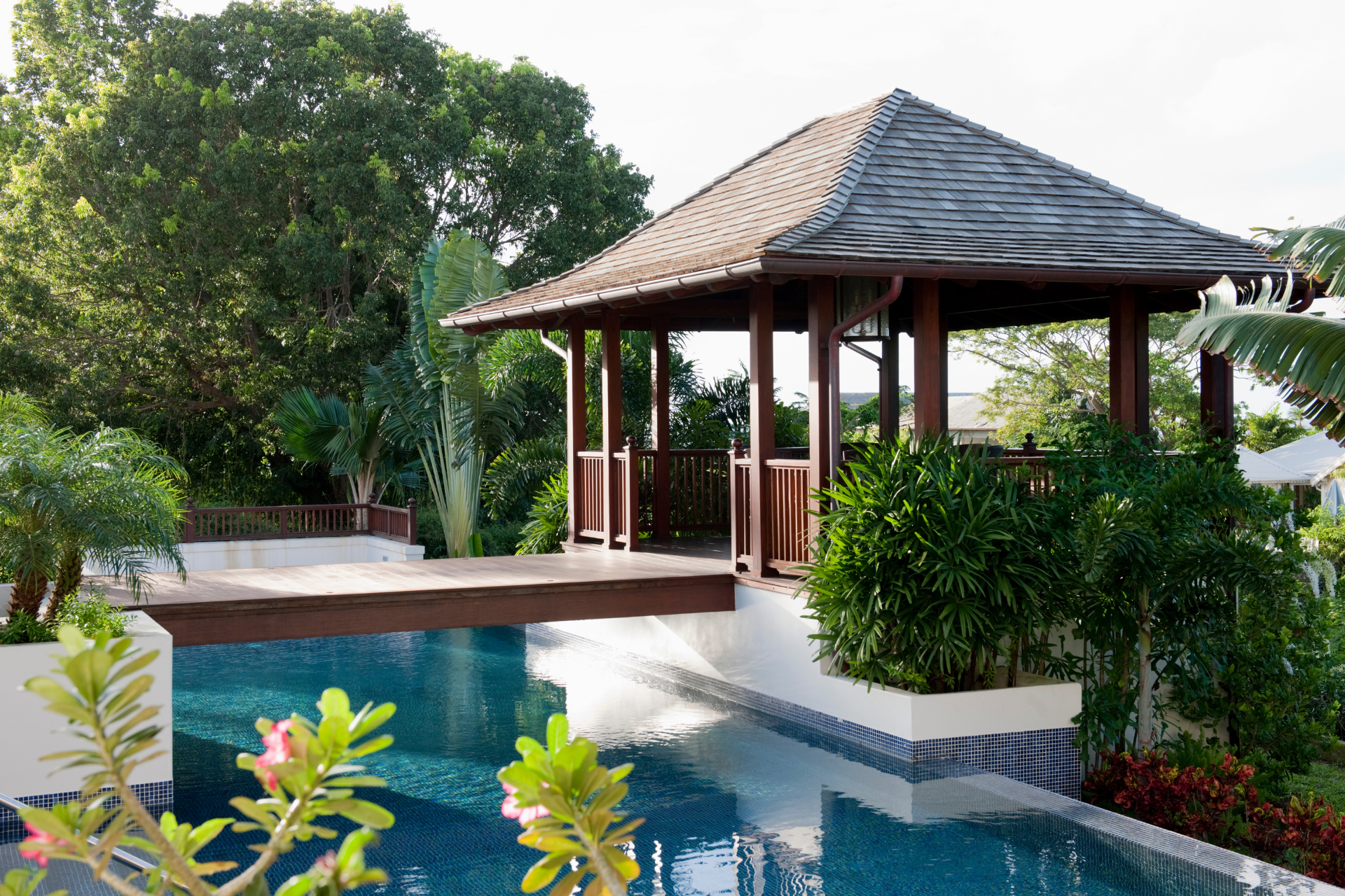 A gazebo overlooking a swimming pool with trees in the background