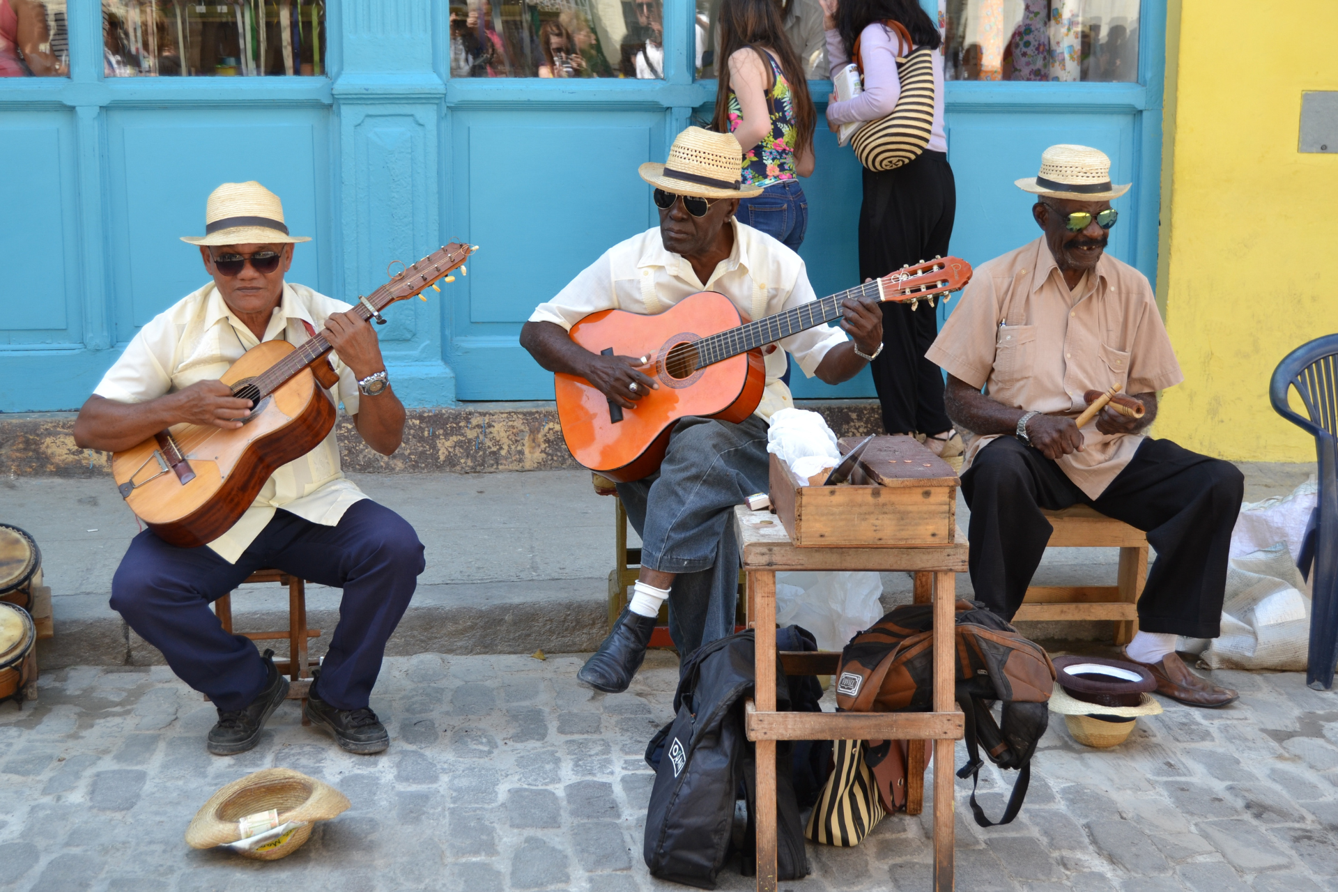 A group of men are playing guitars and drums on the sidewalk.