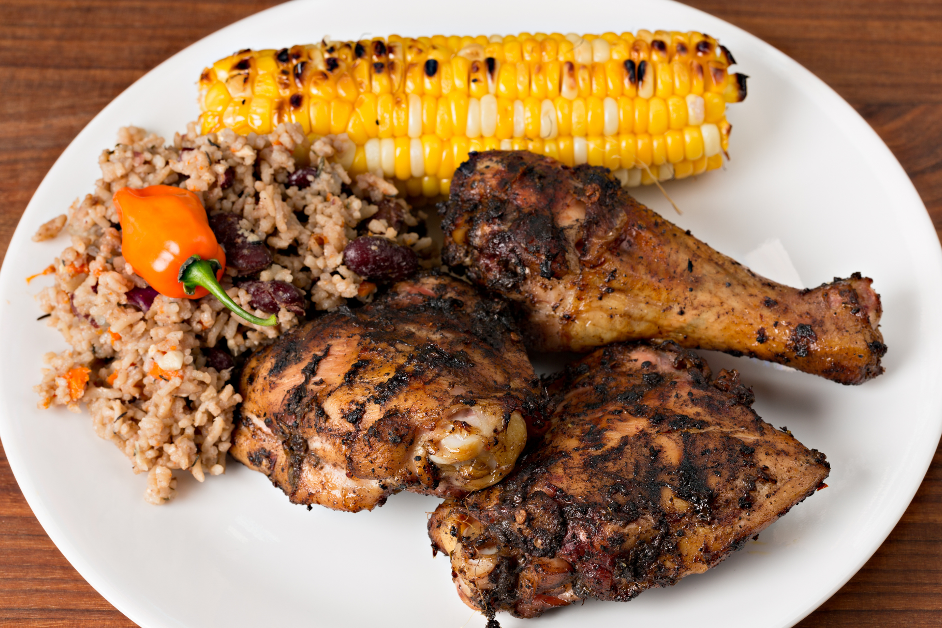 A white plate topped with chicken and corn on the cob