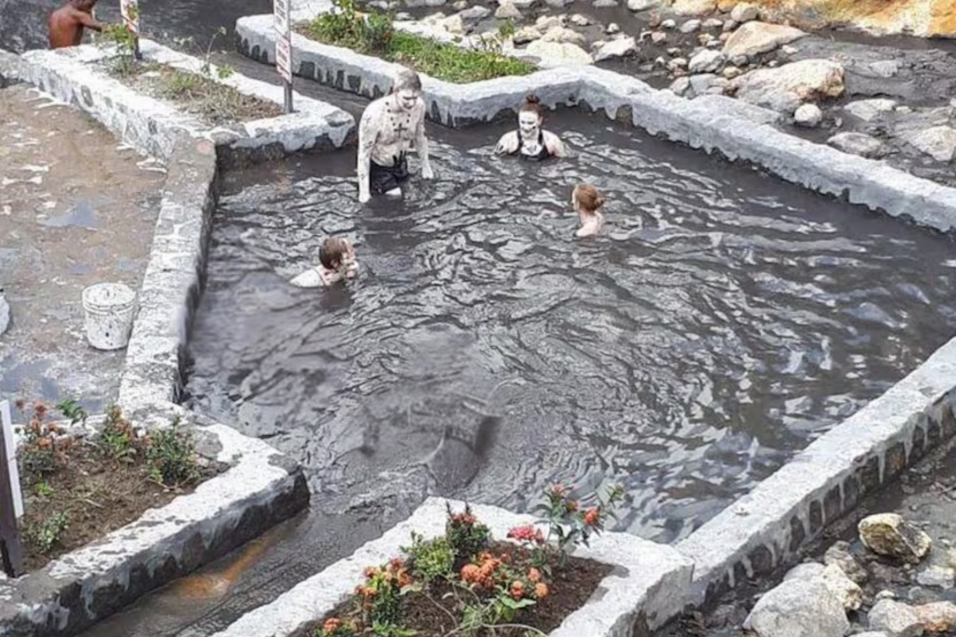 A group of people are swimming in a muddy pool.