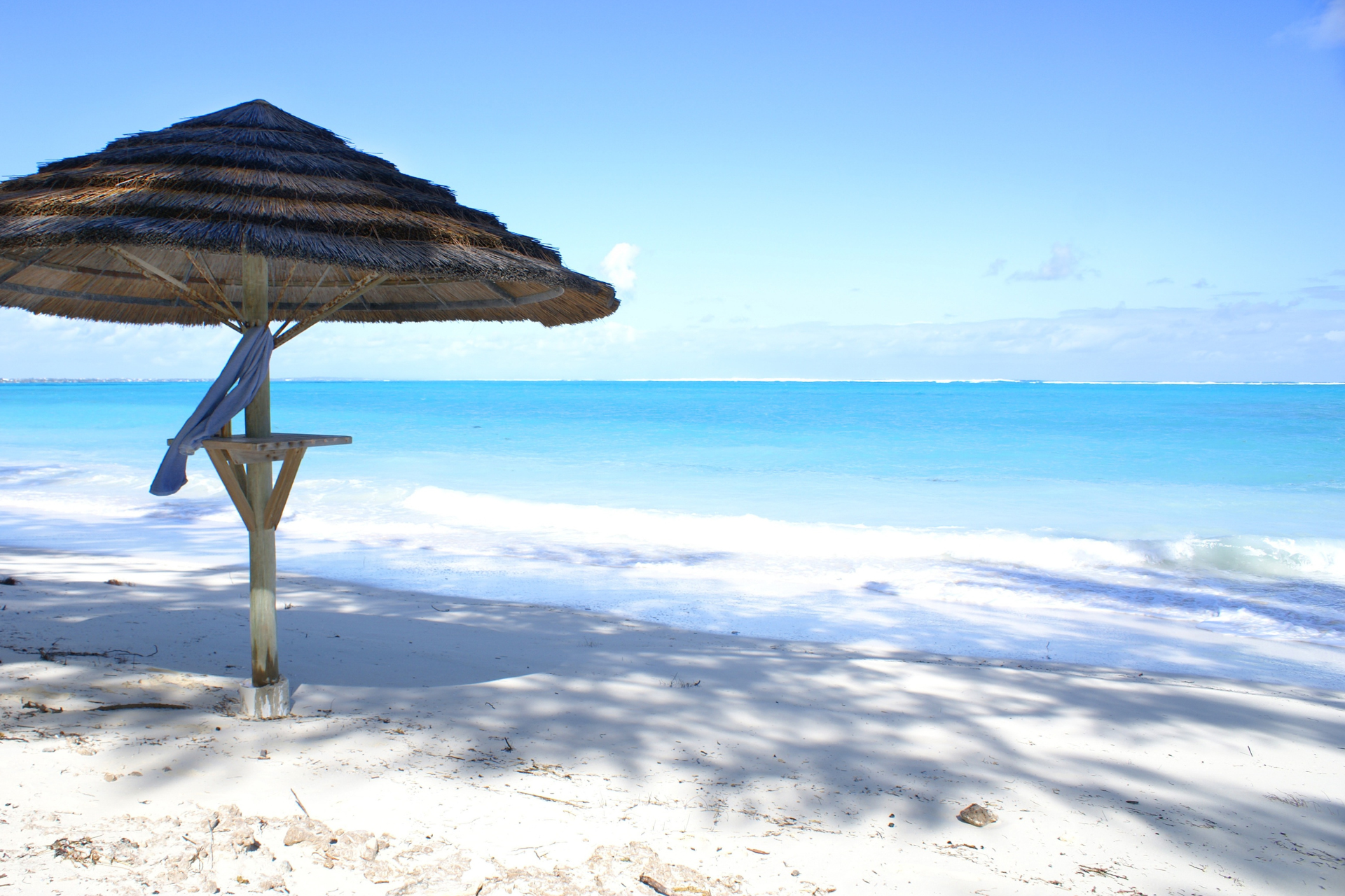 A thatched umbrella on a beach with the ocean in the background