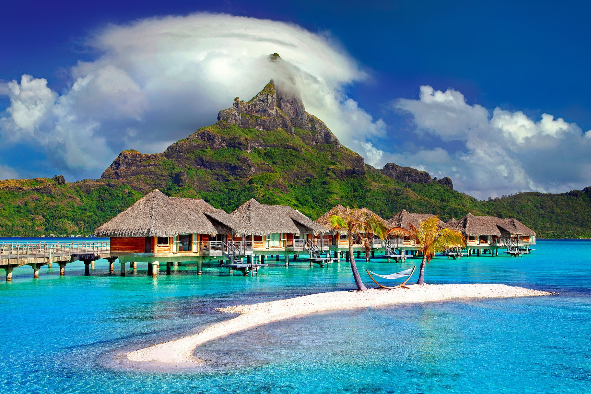 A small island in the middle of the ocean with a mountain in the background.