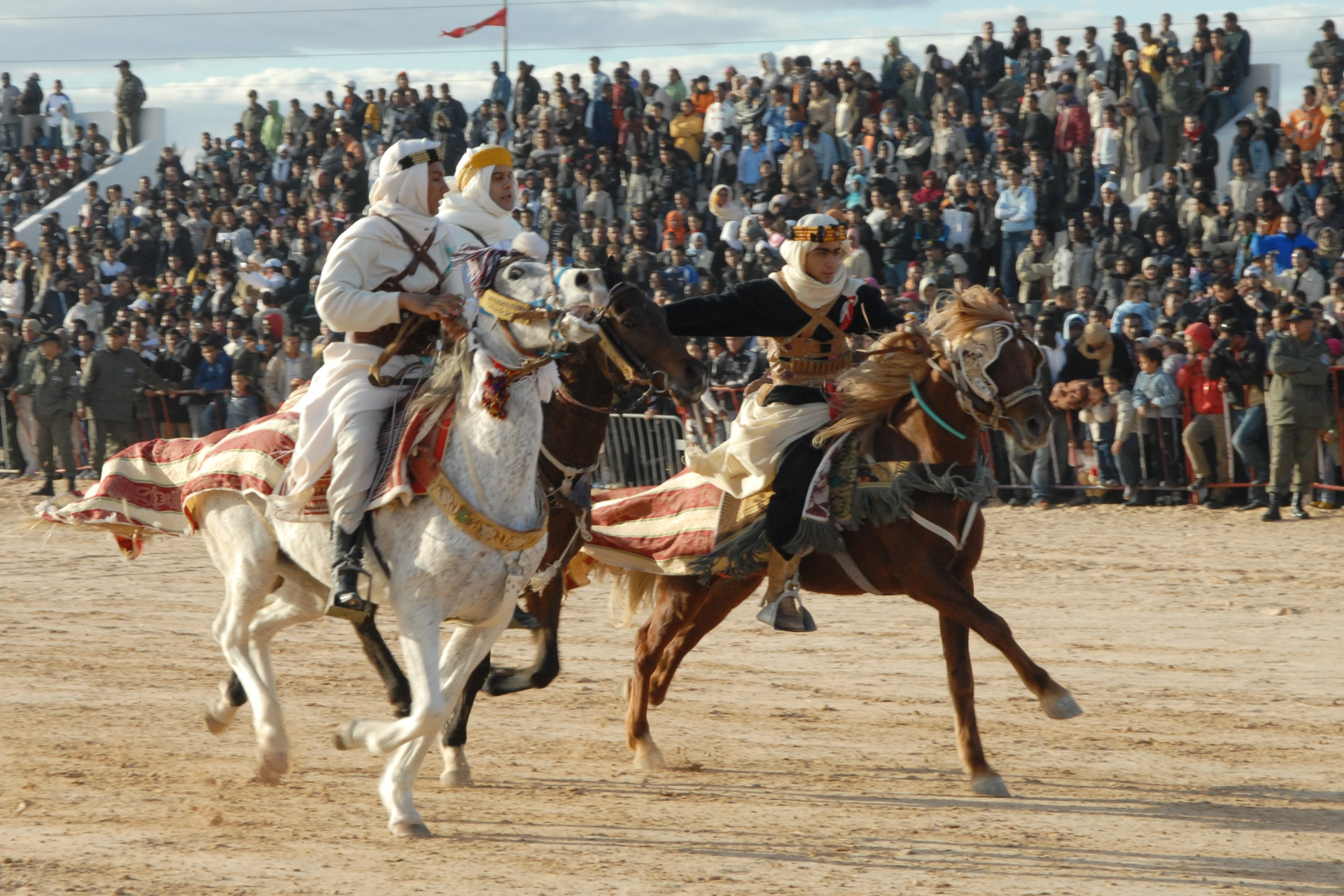 A group of people riding horses in front of a crowd