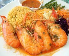 A white plate topped with shrimp , rice and vegetables.