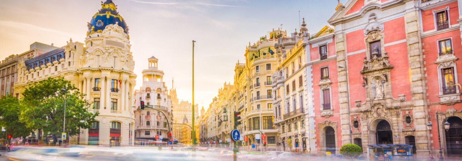 A city street with a lot of buildings and cars driving down it.