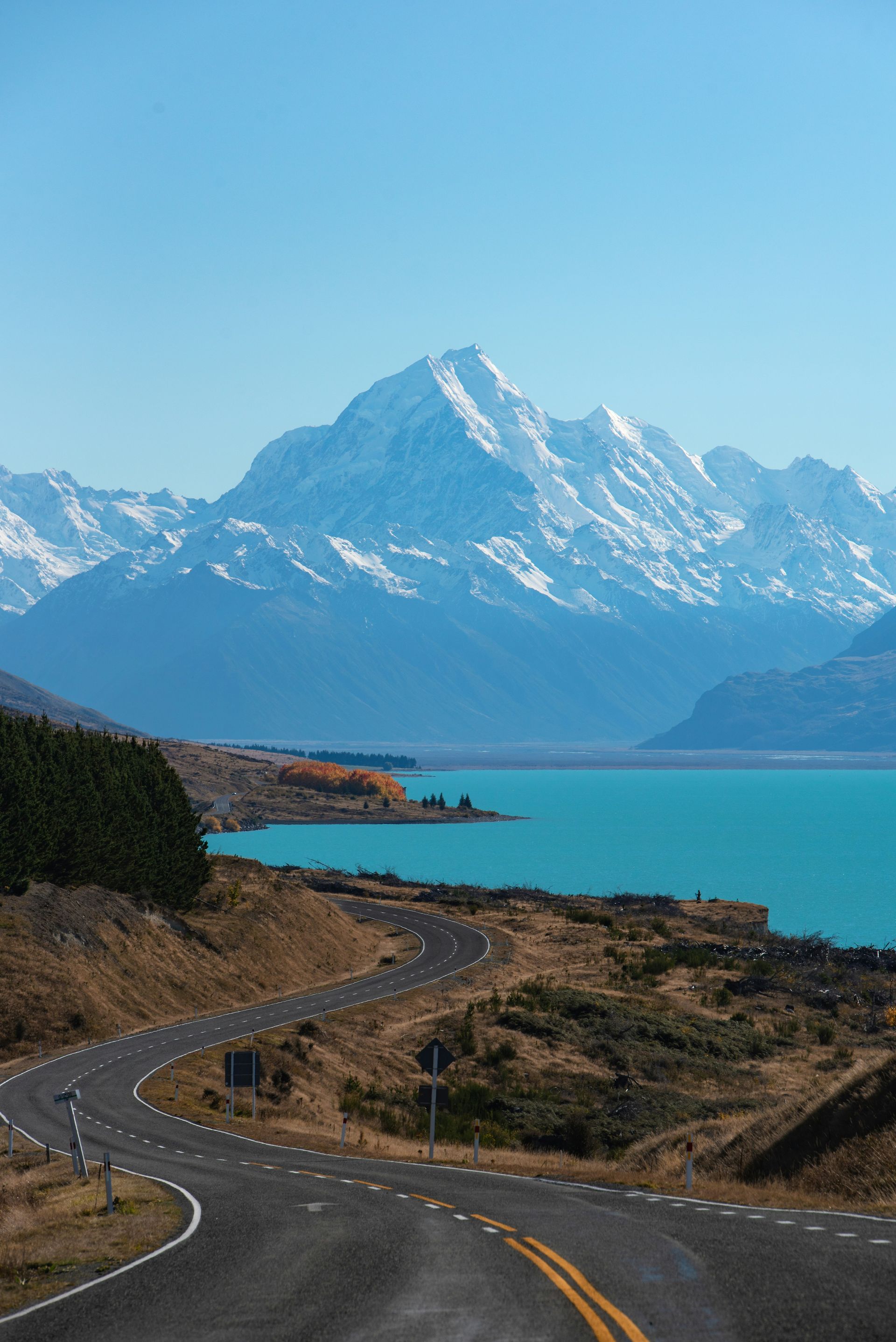 A road leading to a lake with mountains in the background.