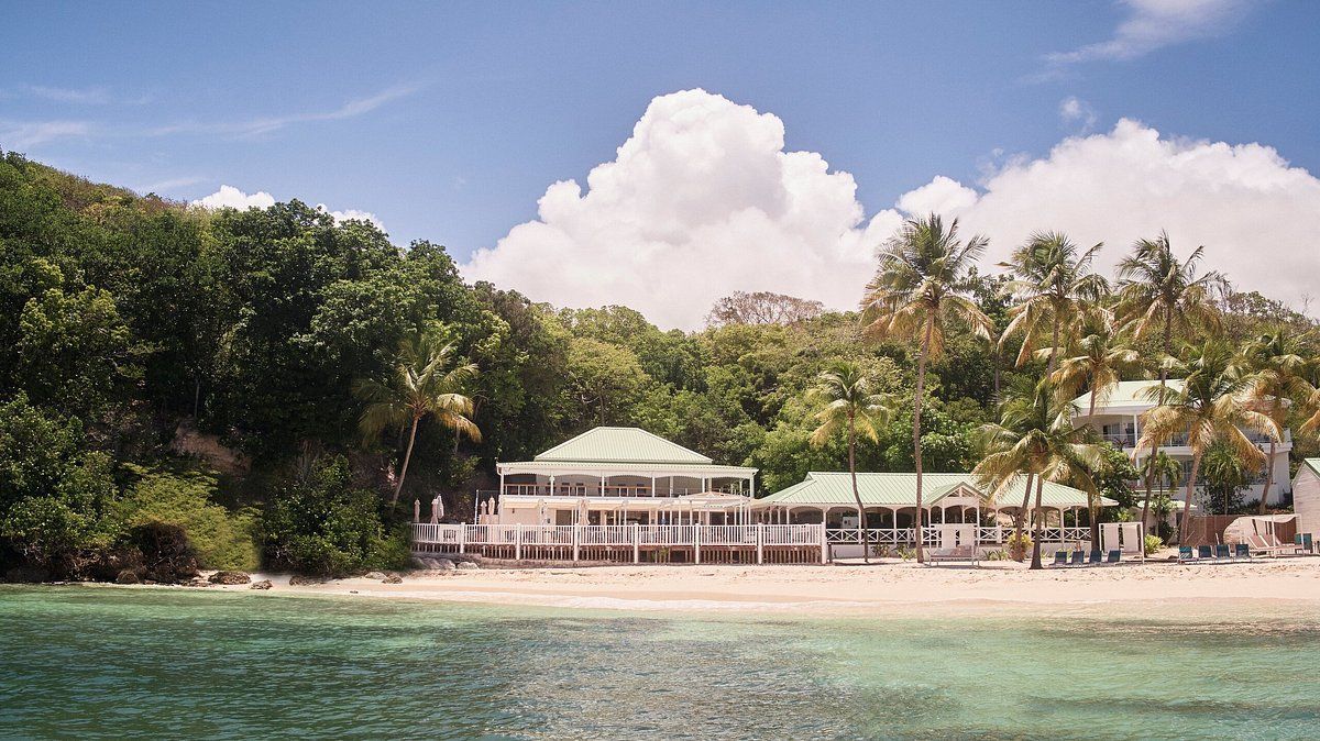 A large white house sits on the shore of a tropical island