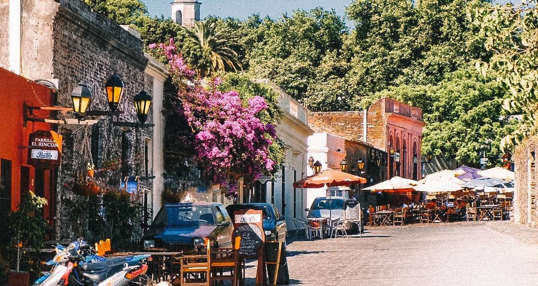 A row of motorcycles are parked on the side of a cobblestone street.