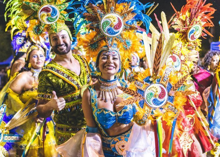 A group of people dressed in colorful costumes are dancing in a carnival parade.