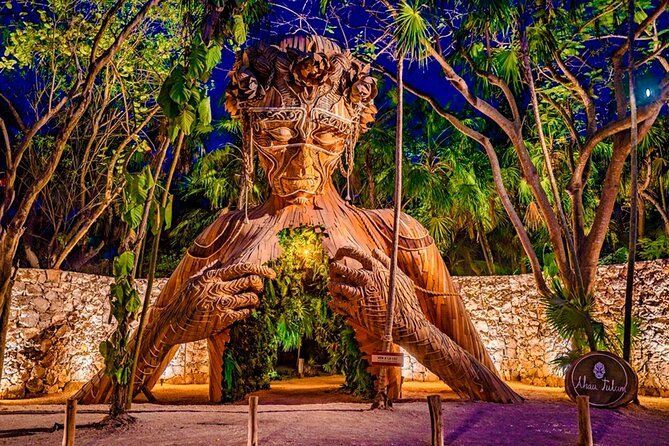 A large statue of a woman is surrounded by trees at night.