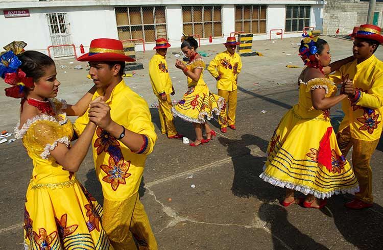 A group of people in yellow dresses and hats are dancing