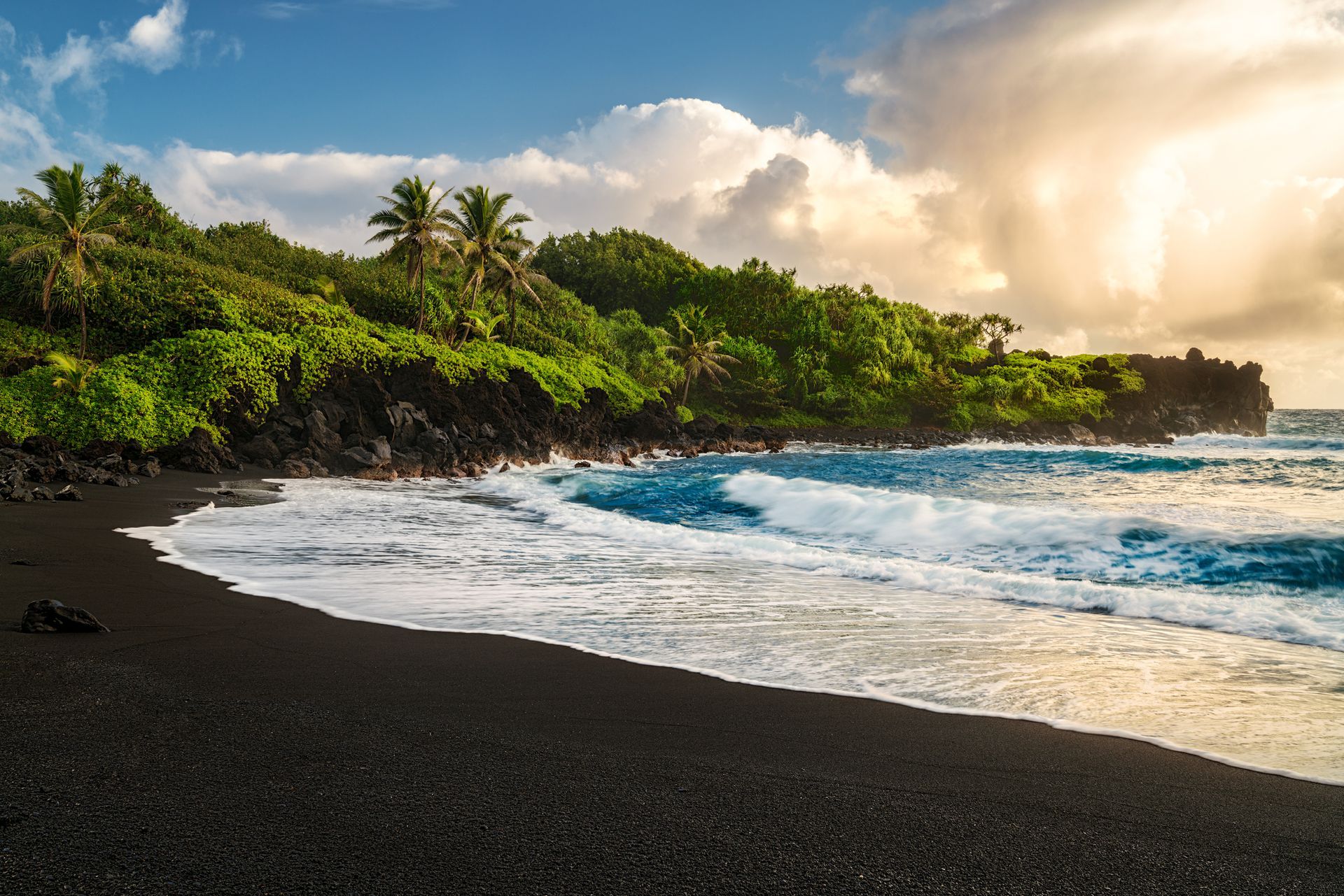 A black sandy beach with waves crashing on it