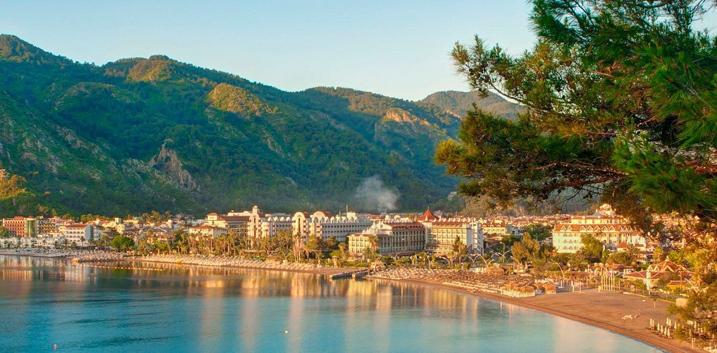 A beach with a city in the background and mountains in the background.