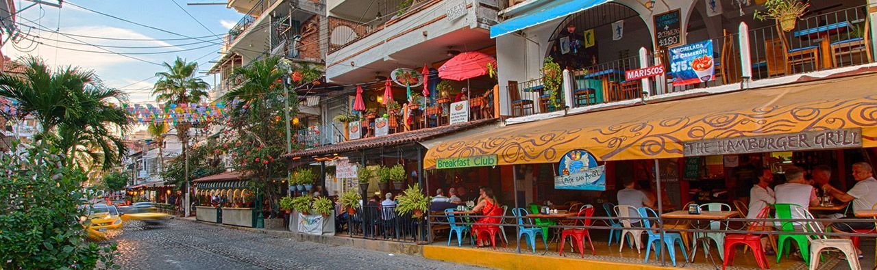 A group of people are sitting at tables outside of a restaurant.