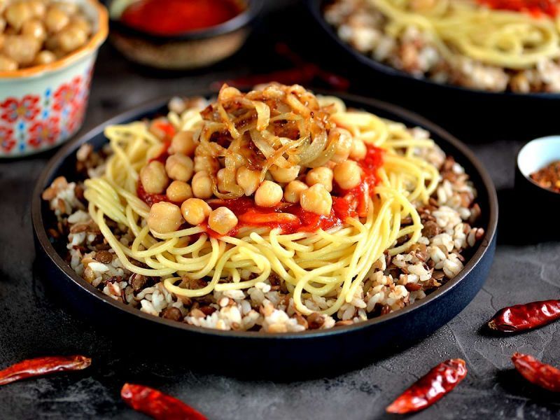 A close up of a plate of food with noodles and chickpeas on a table.