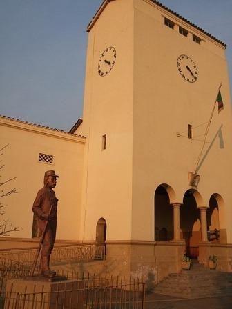 A statue in front of a building with a clock on it