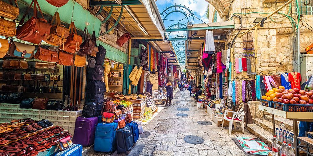 A narrow street filled with lots of shops and luggage.