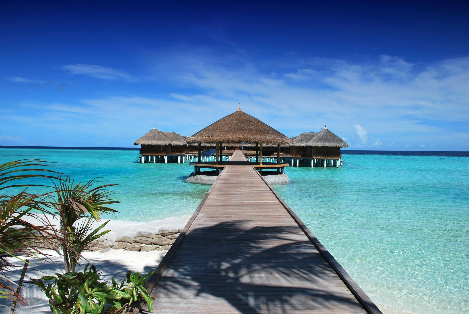 A wooden pier leading to a hut in the middle of the ocean.