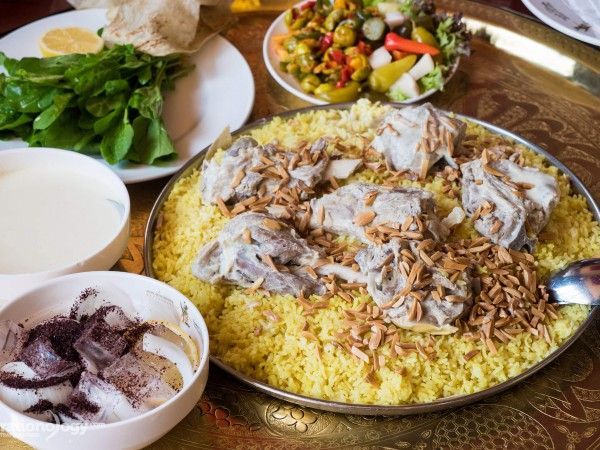 A plate of food with rice , meat and vegetables on a table.