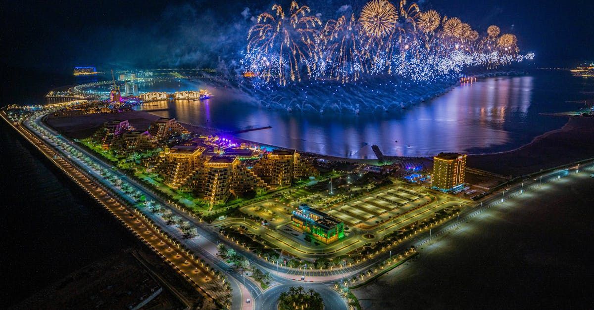 An aerial view of a city at night with fireworks over the water.