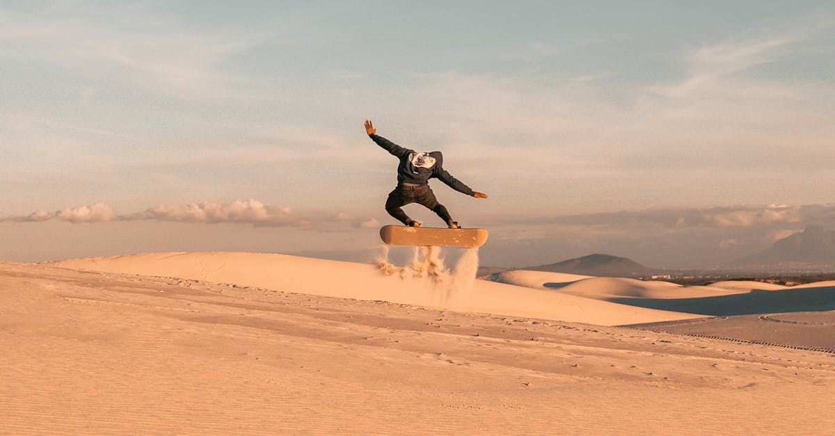 A man is riding a snowboard on top of a sand dune.