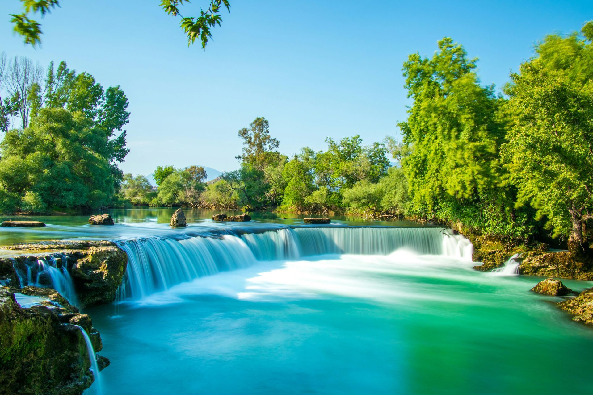 There is a waterfall in the middle of a river surrounded by trees.