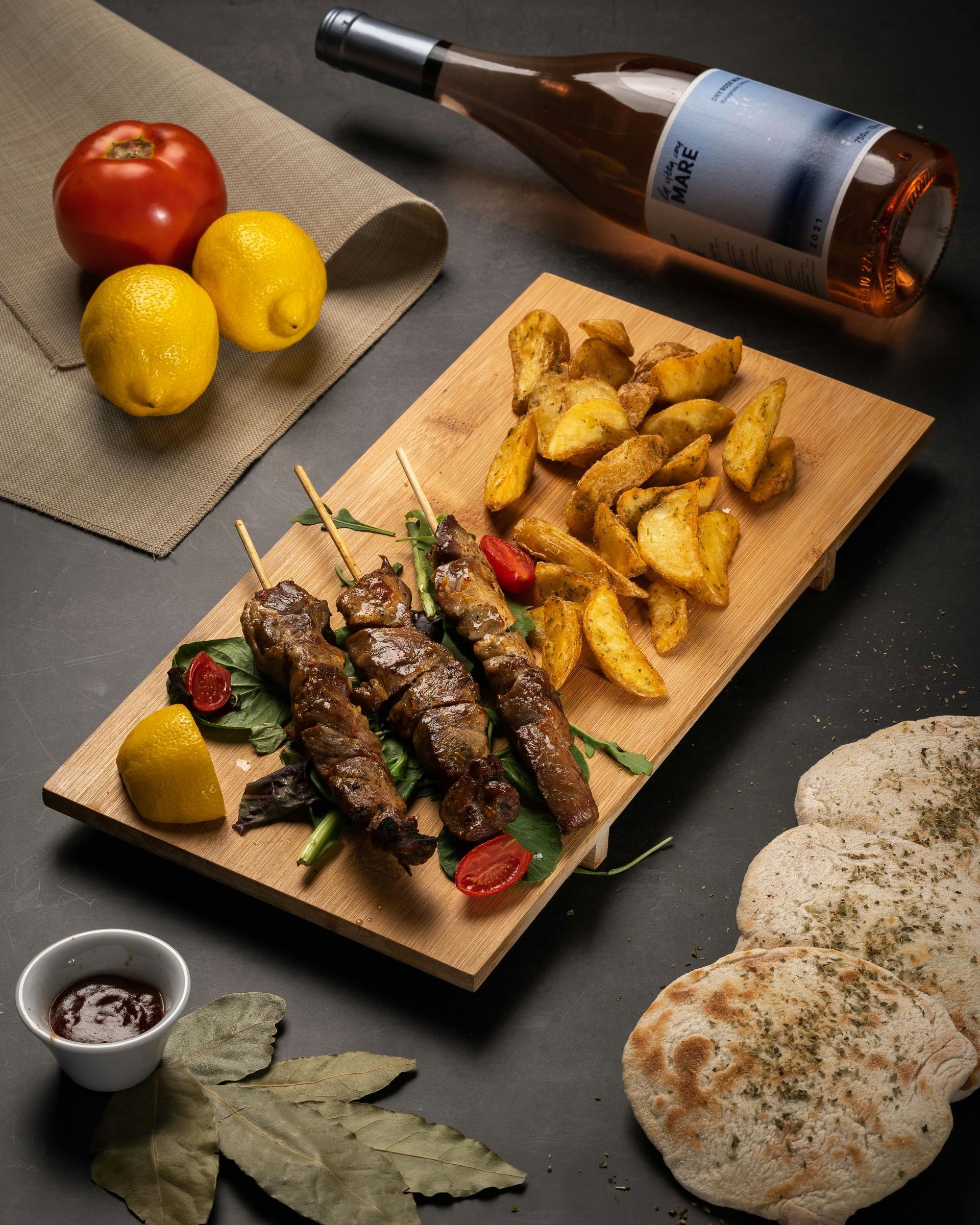 A wooden cutting board filled with food and a bottle of wine