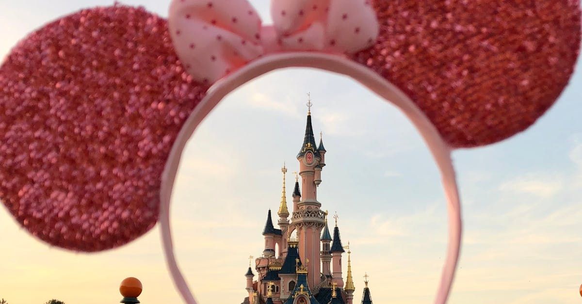 A pink headband with minnie mouse ears and a castle in the background.