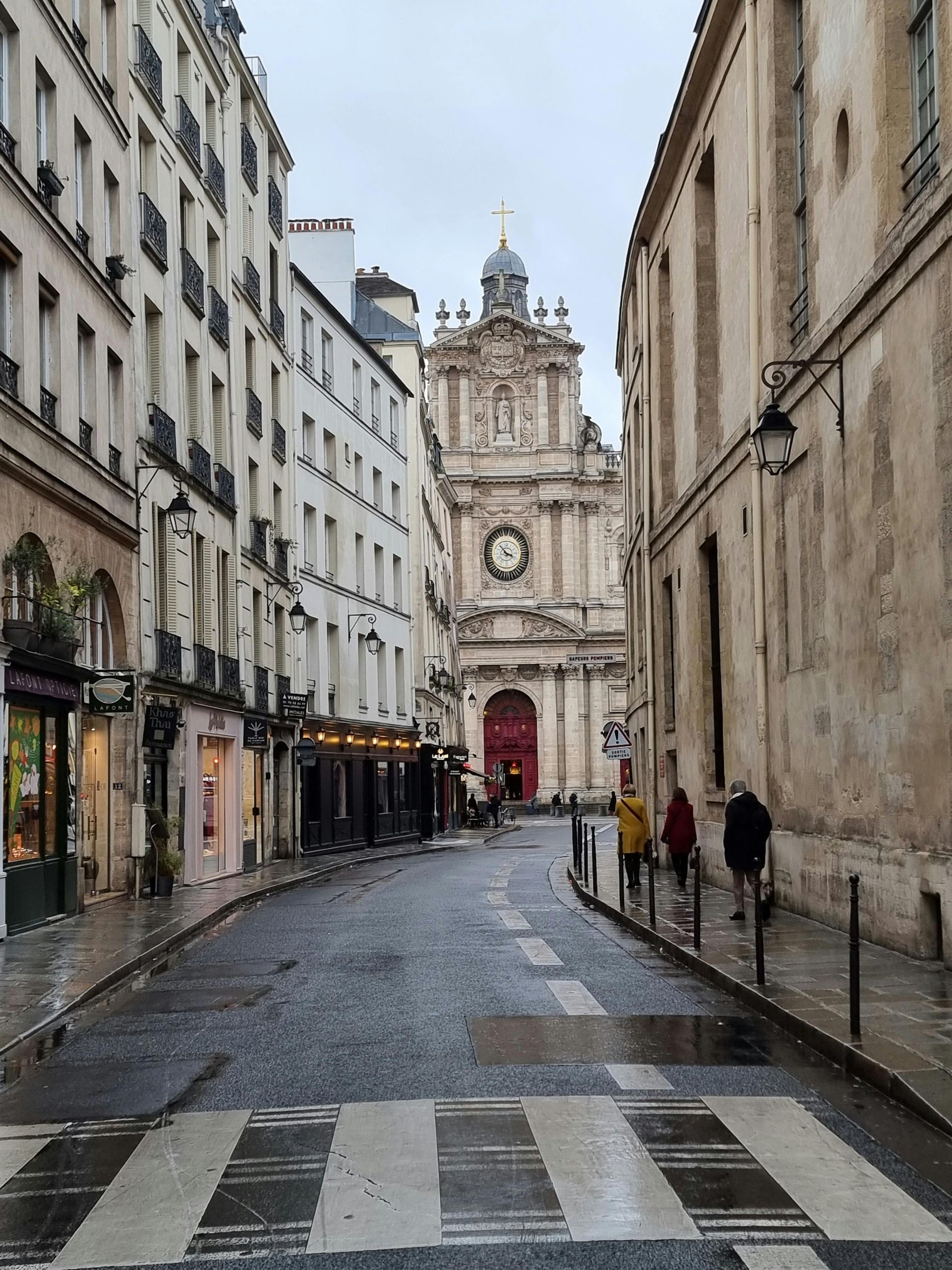 A city street with a crosswalk and a church in the background