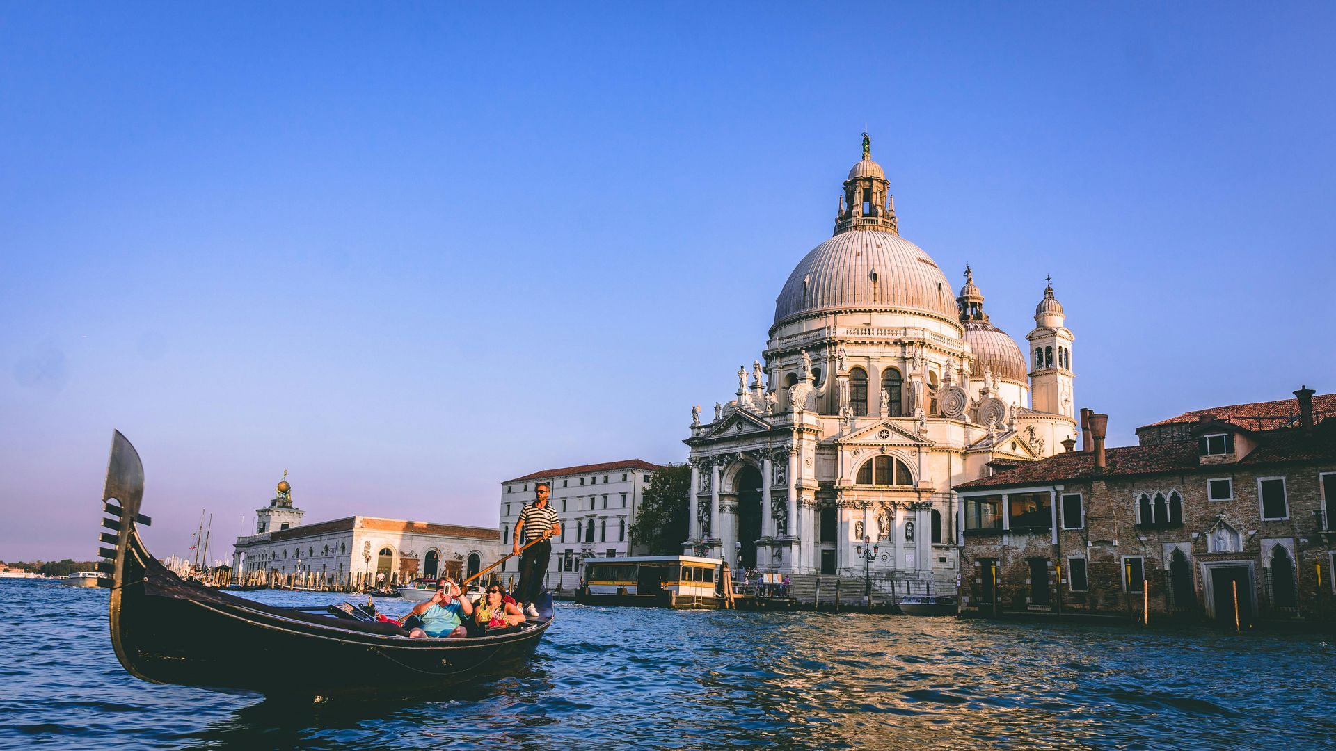 A gondola is floating on a body of water in front of a large building.