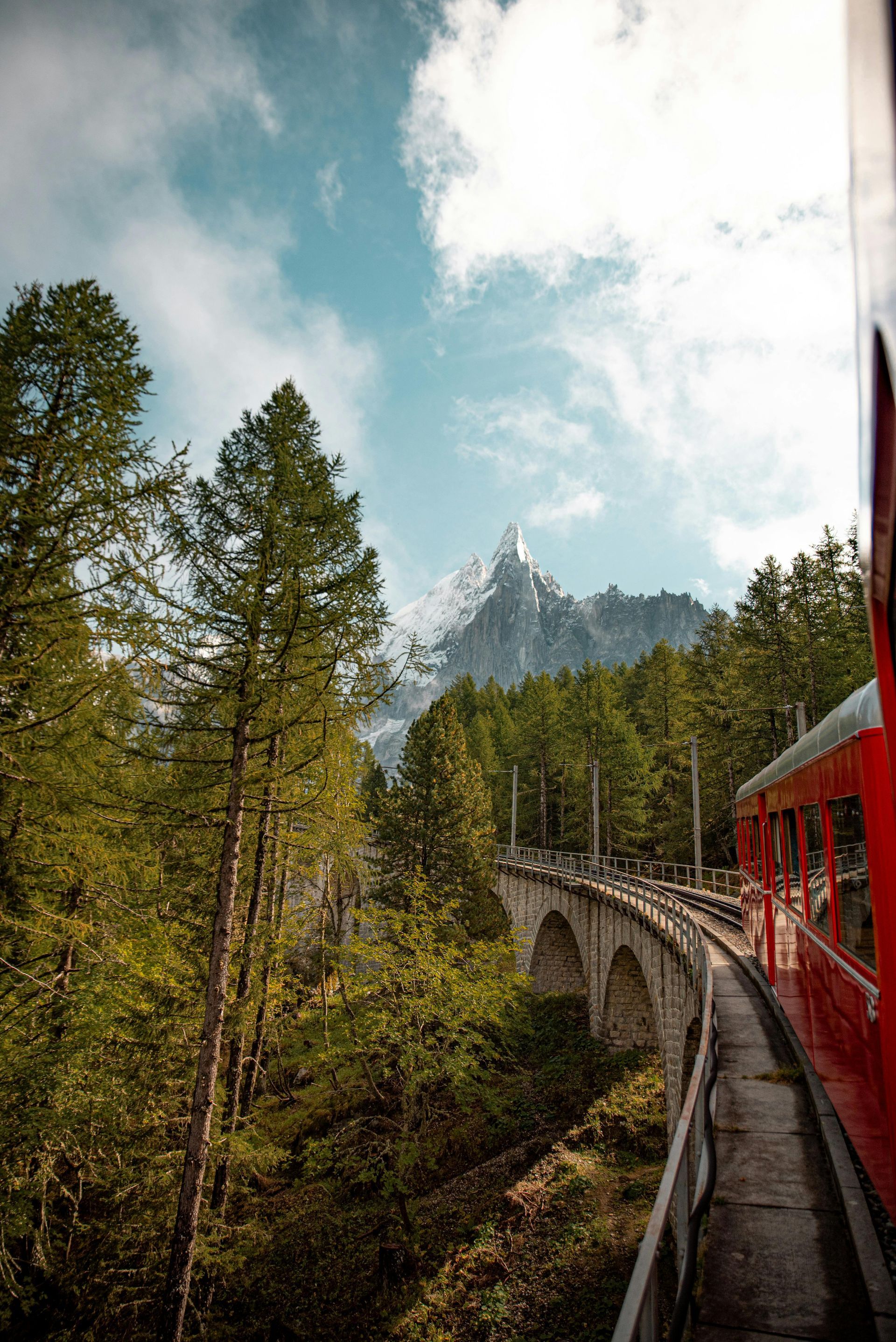 A train is going over a bridge in the mountains.