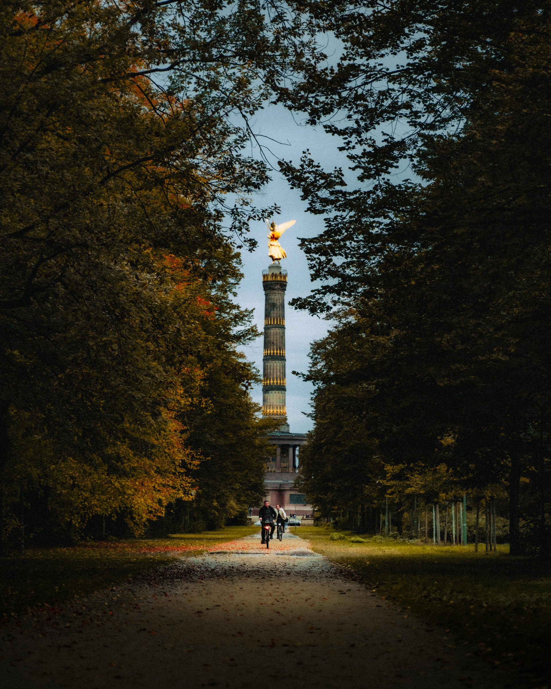 A couple riding bikes down a path with a tower in the background