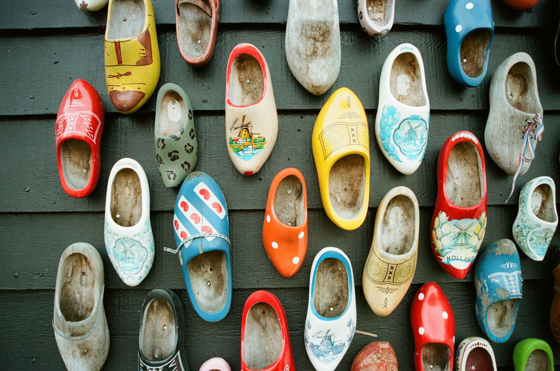 A bunch of colorful shoes are hanging on a wall