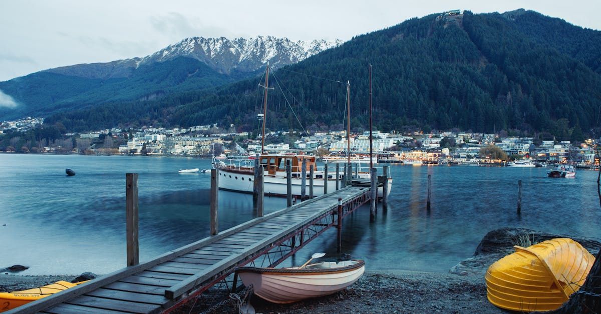 A dock with boats docked on it and mountains in the background.