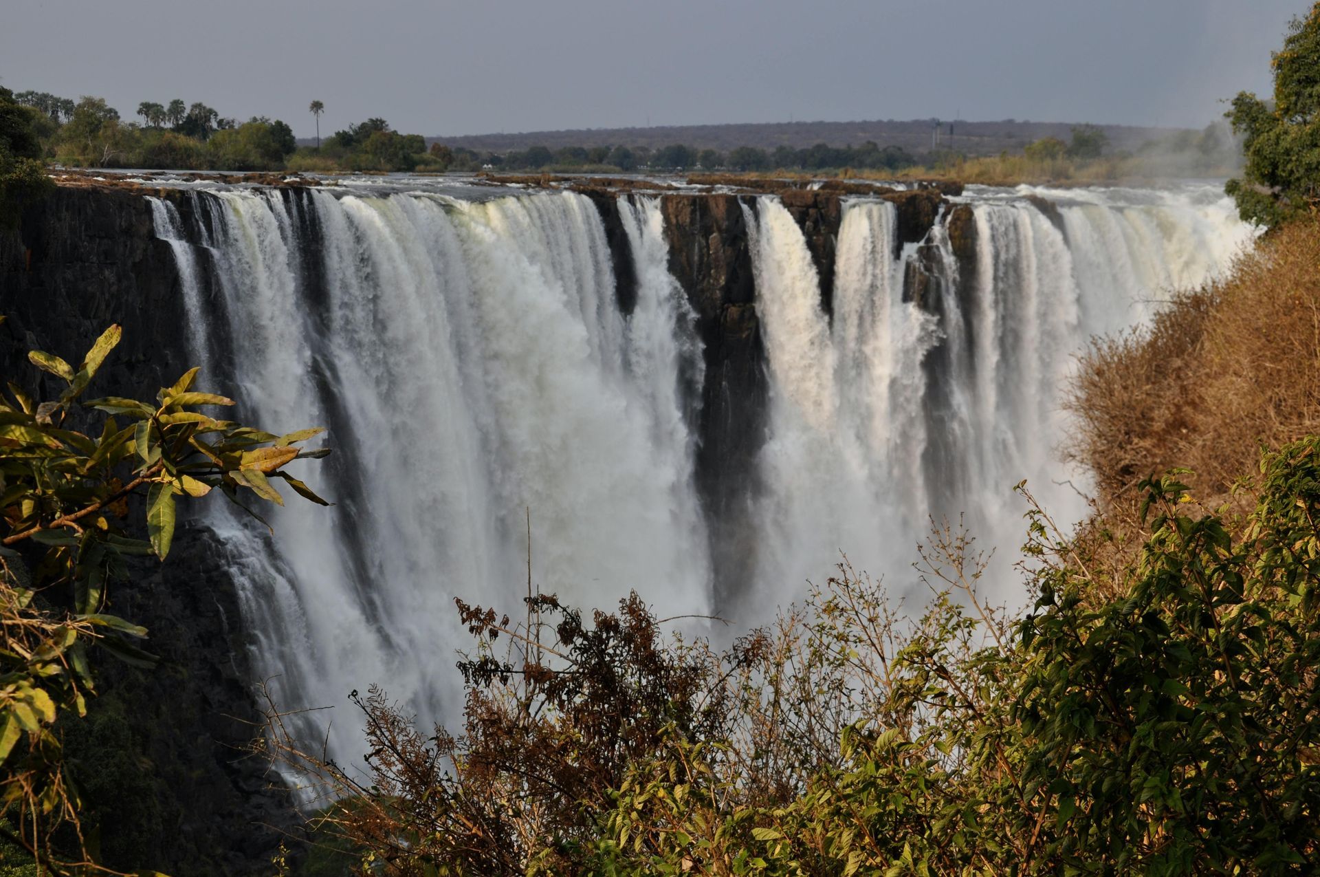 A large waterfall is surrounded by trees and bushes