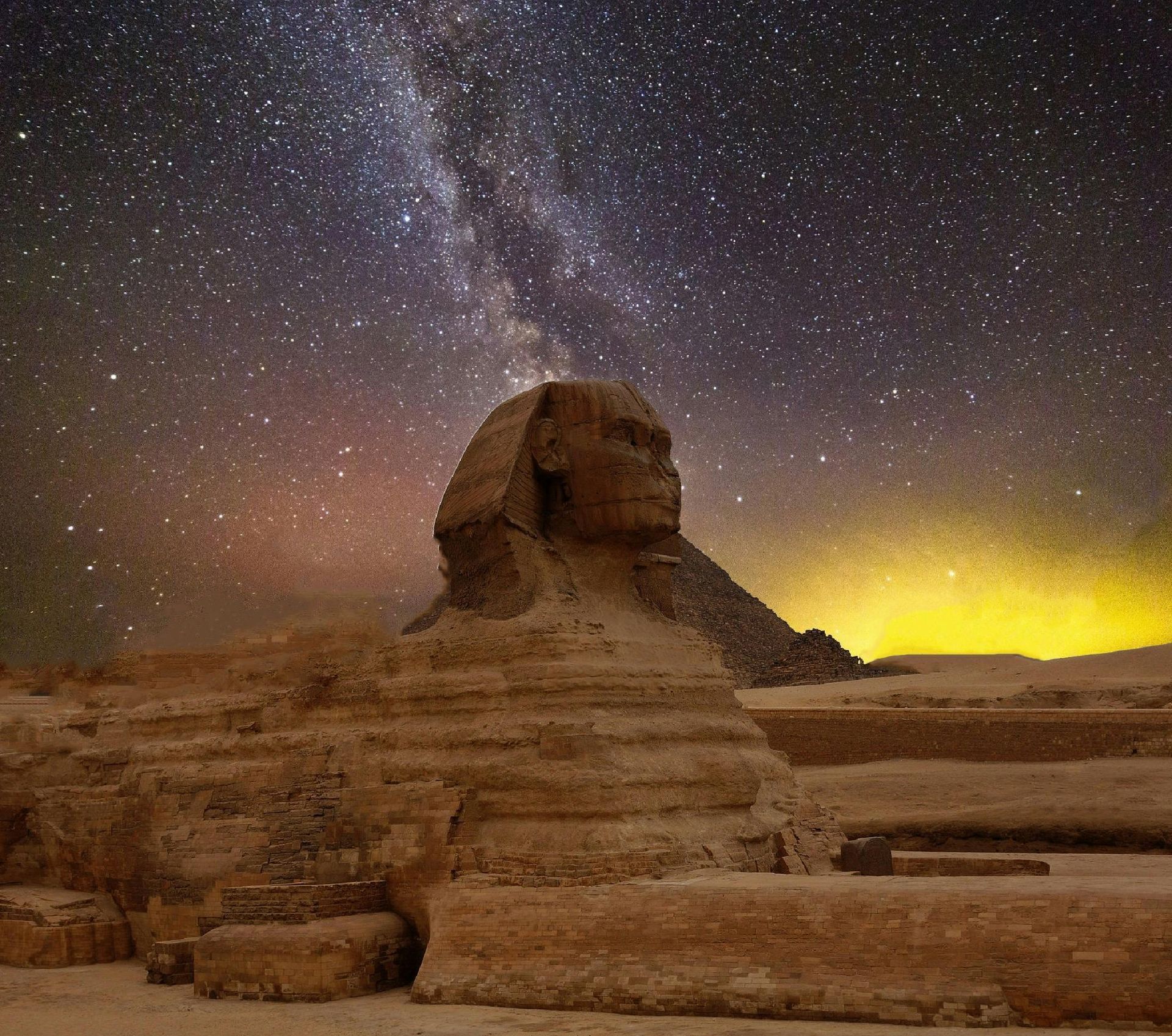 The sphinx is lit up at night under a starry sky