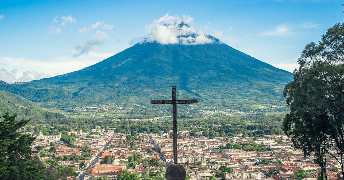 There is a cross in the foreground and a mountain in the background.