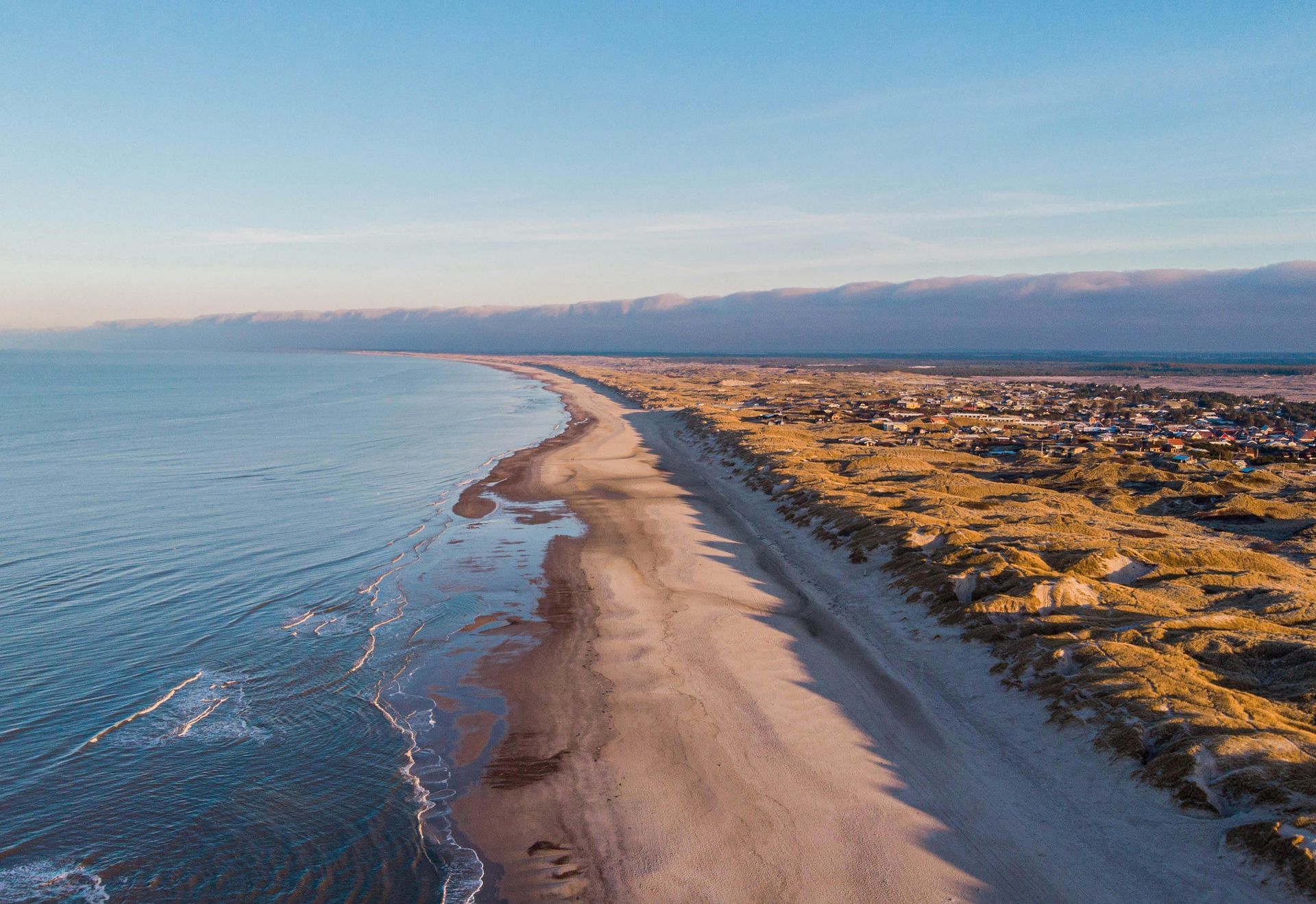 An aerial view of a long sandy beach next to the ocean.