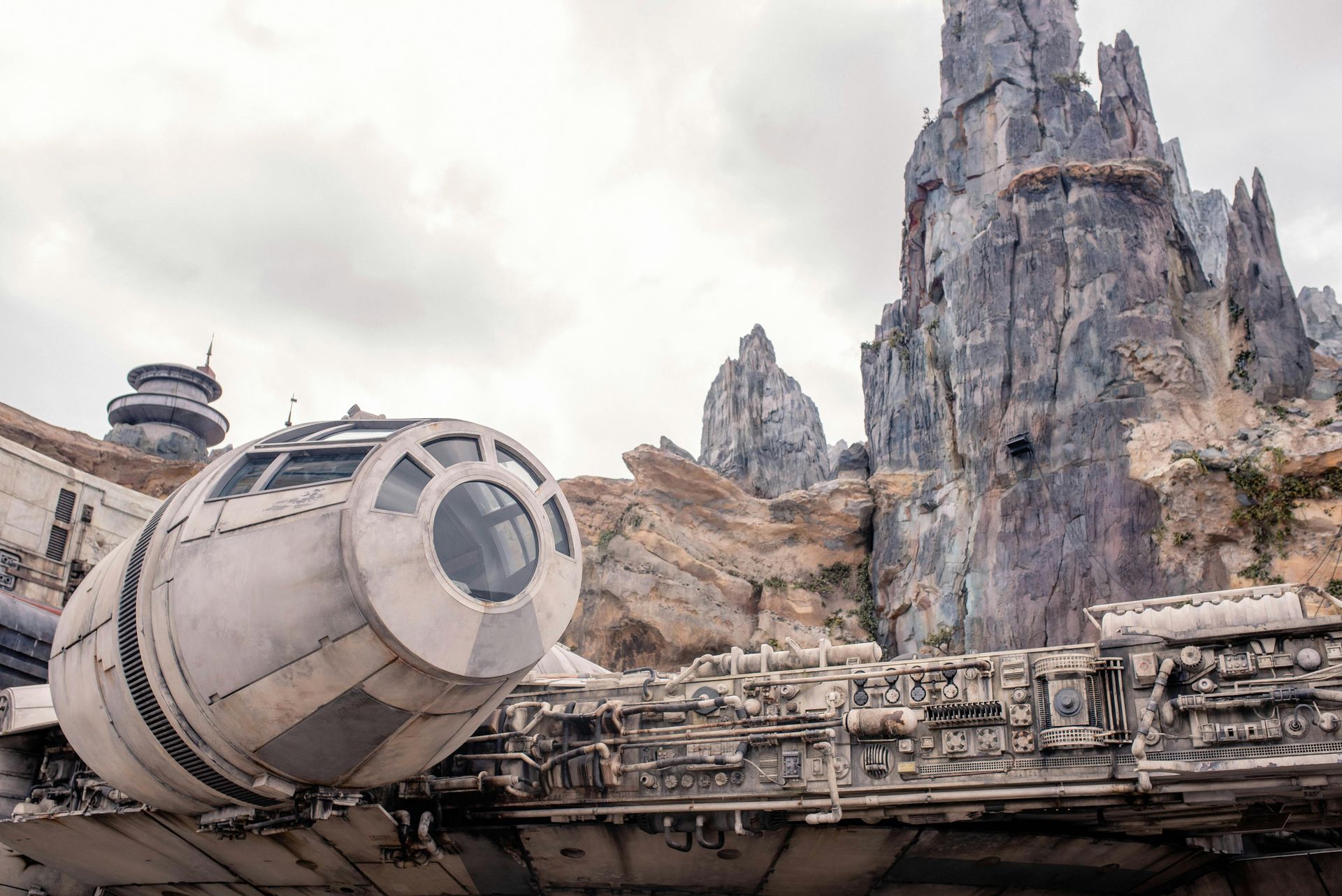 A large space ship is parked in front of a mountain.